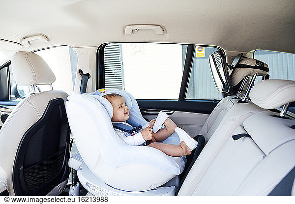 Baby boy sitting in child's seat and looking in mirror in a car