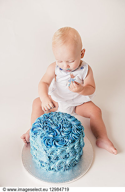 Baby boy testing blue birthday cake