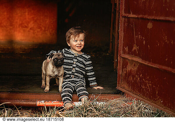 baby boy toddler with a pug puppy sitting down