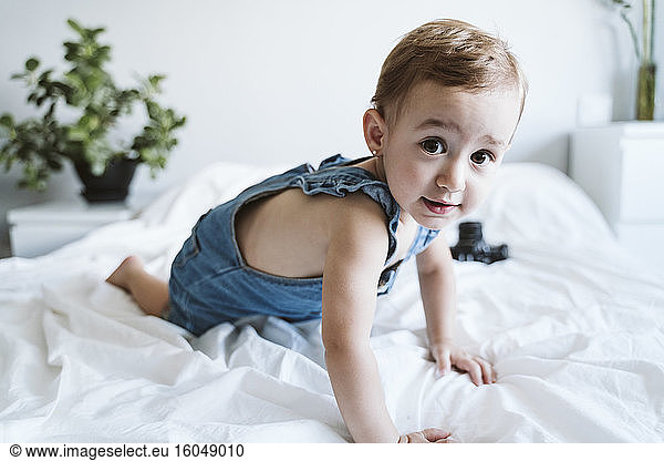 Baby girl crawling on bed