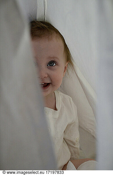 baby girl hiding behind sheet