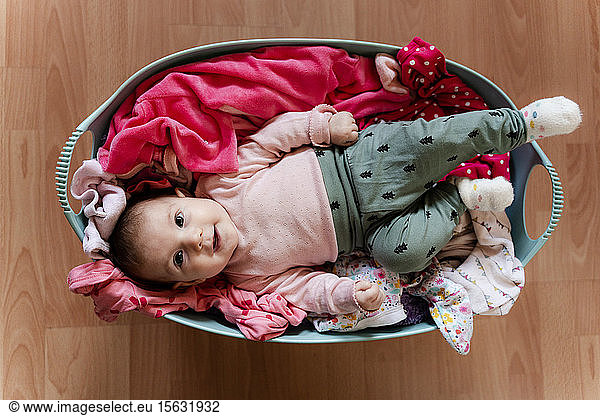 Baby girl in the laundry basket with clothes to clean