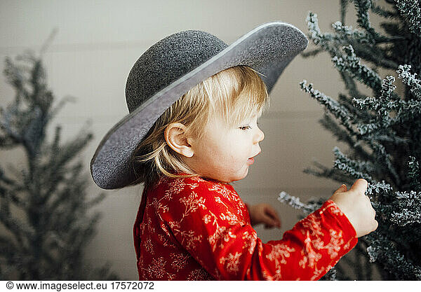 Baby girl looking at Christmas tree with hat