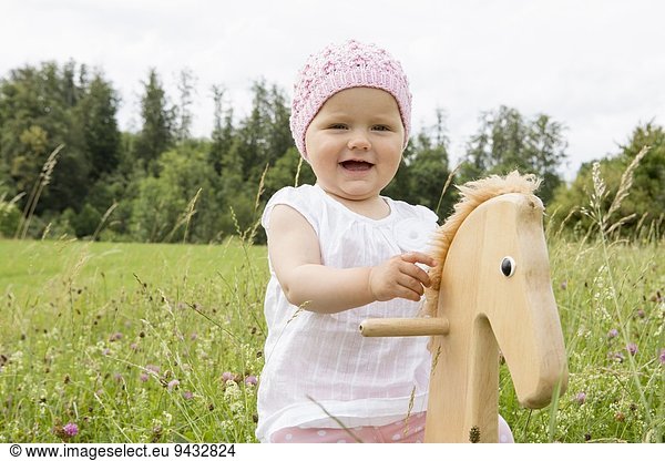 Baby girl playing on hobby horse