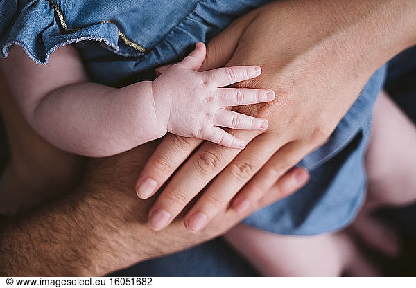 Baby girl's hand on father and mother at home