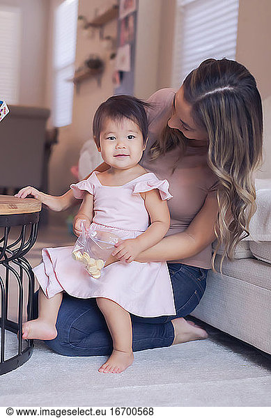 Baby girl's snack time with mom in the living room