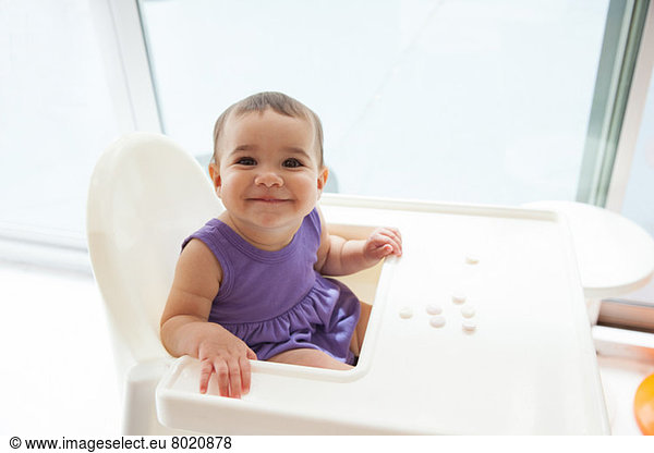 Baby girl sitting in high chair smiling  portrait