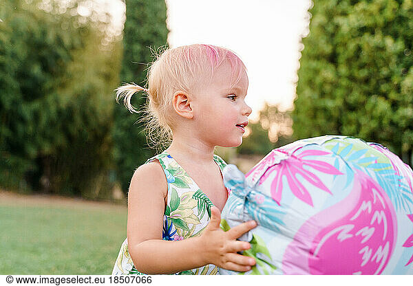 Baby girl two years old plays balloons on the grass  summer party