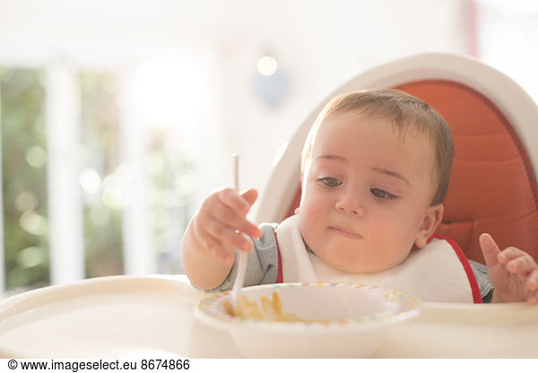 Baby Junge isst im Hochstuhl