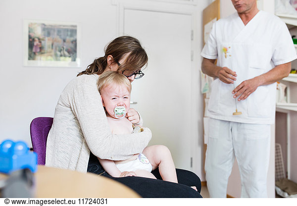 Baby (12-17 months) with mother and doctor in examination room