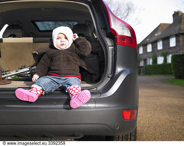 Baby sitting in open car boot