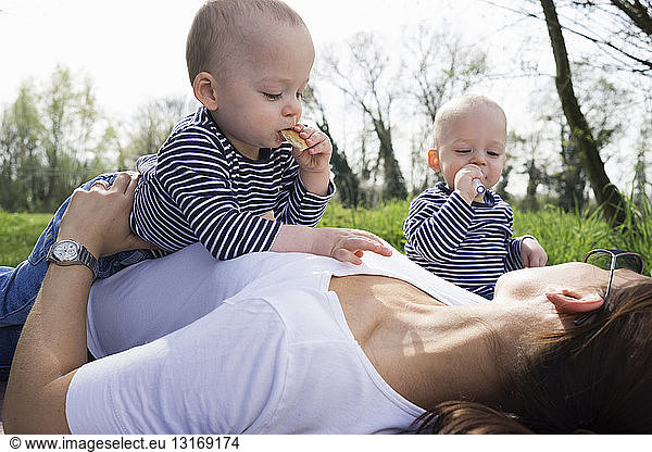 Baby twin brothers and mother having picnic in field