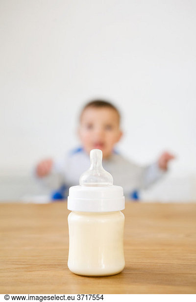 Babyflasche im Vordergrund und Baby im Hintergrund