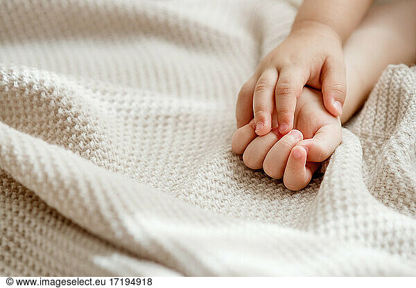 Babyhände  die auf einer Strickdecke ruhen