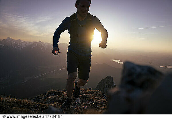 Back lit man running on rocky mountain
