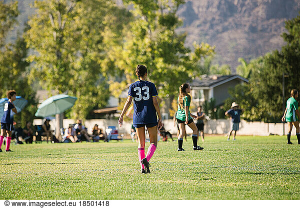 Back of girl soccer player walking on the field