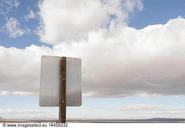 Back of road sign against blue sky and clouds