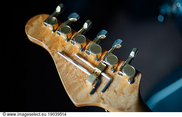 Back of the headstock of the electric guitar with golden tuners.