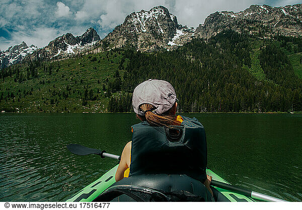 Back of young girl Kayaking in an alpine lake