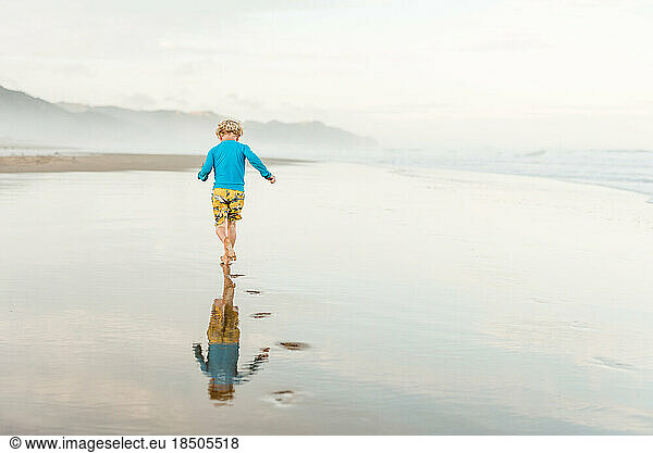Back view of child running on a beach with footprints