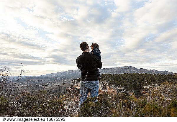 Back view of father carrying little son in Siurana mountains