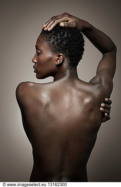 Back view of nude woman with hand on head
