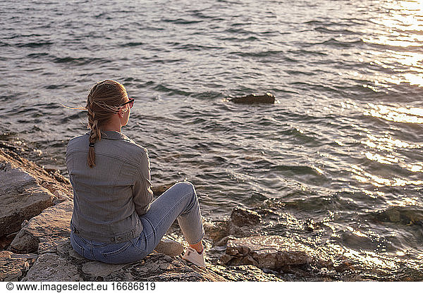 Back view of woman sitting by the sea