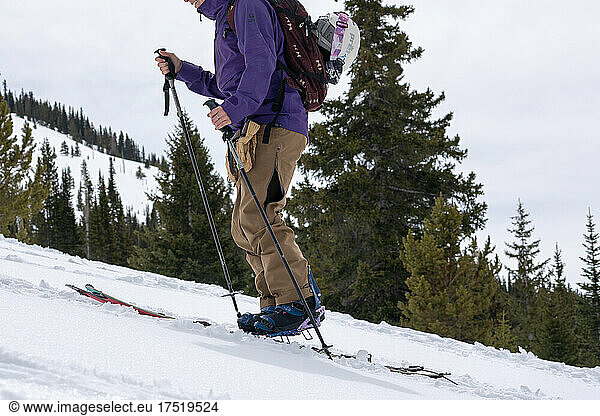 Backcountry Snowboarder skinning uphill on snow covered mountain