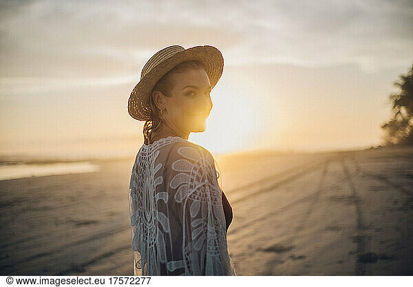 backlighting portrait of a blond girl wearing a hat on the beach