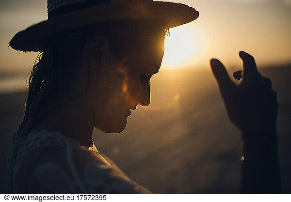 backlighting portrait of a girl wearing a hat during the sunset