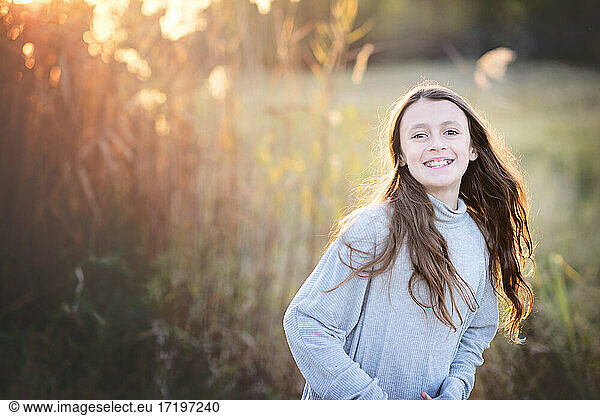 Backlit beautiful young tween girl with long hair outdoors in Fall.