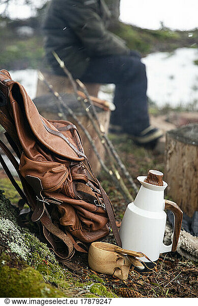 Backpack kept by jug and wooden cup