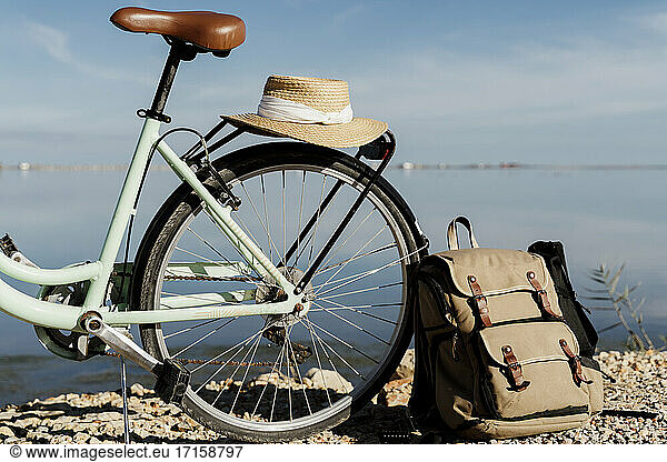 Backpack leaning on bicycle with hat at Ebro Delta against sky on sunny day  Spain