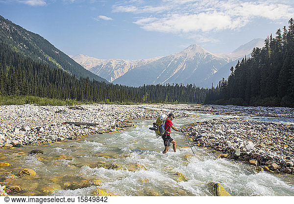 Backpacker crosses icy river in British Columbia  Canada.