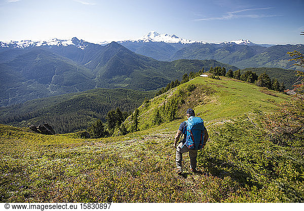 Backpacker hiking on high alpine ridge in the Cascade Mountain Range.