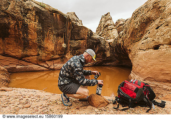 backpacker prepares to treat his drinking water with iodine in desert