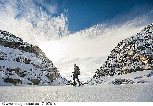 Backpacker traverses winter landscape between two mountains.