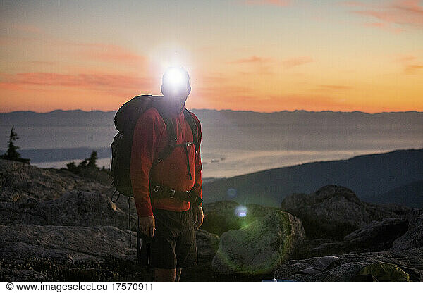 Backpacker uses headlamp while hiking at twilight.