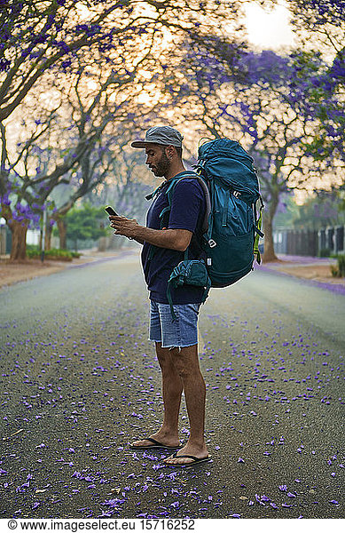 Backpacker using smartphone standing on a street  Pretoria  South Africa
