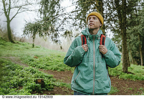 Backpacker wearing raincoat hiking in forest