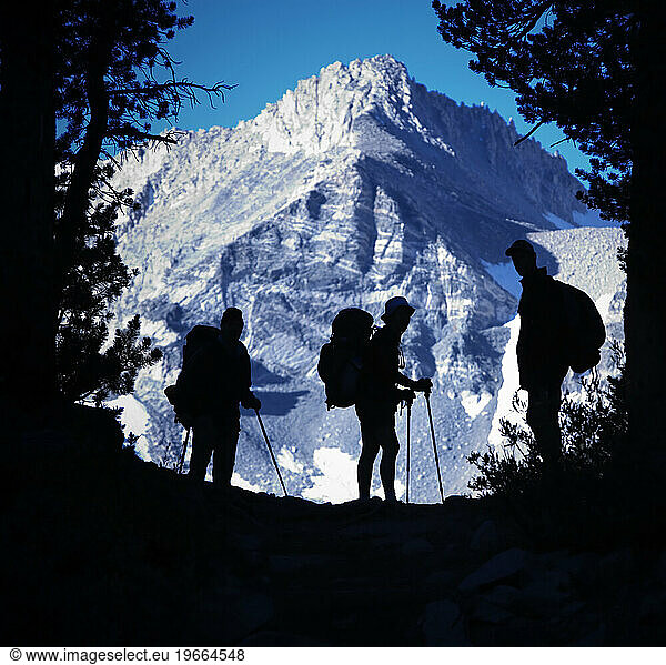 Backpackers silhouetted against a mountain.