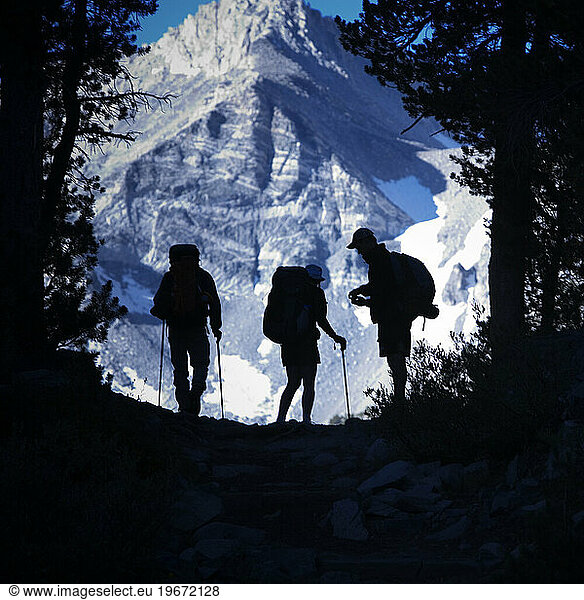 Backpackers silhouetted against a mountain.