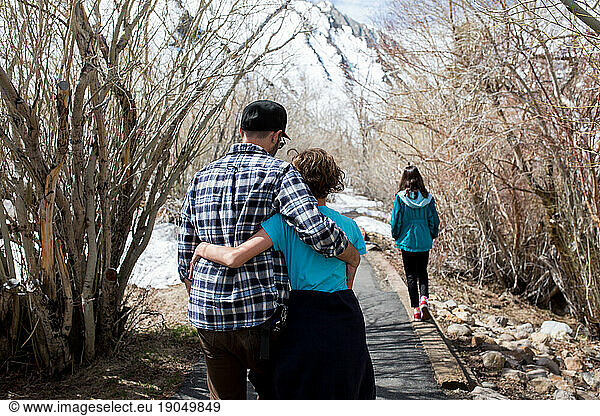 Backside view of father and daughter embracing as they walk in nature