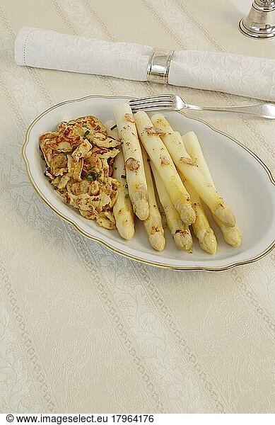 Baden cuisine  asparagus with crisp  flädle  pancakes made of potato dough torn into pieces with white asparagus  vegetables  healthy  hearty  from the pan  vegetarian  typically Baden  traditional cuisine  serving platter  napkin ring  napkin  table bell  fork  silverware  food photography  studio  Germany  Europe
