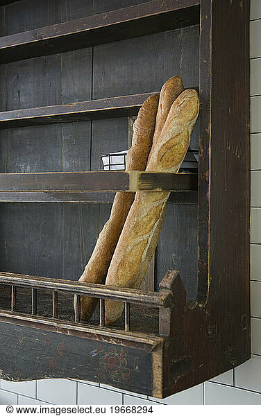 Baguettes in wooden wall rack at a restaurant.