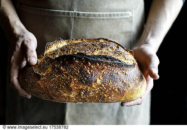 Baker holding loaf of fresh baked bread
