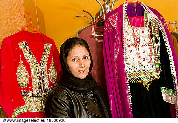 Bakhtnazira poses with traditional clothes for sale in her Kabul shop.