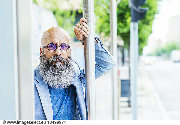 bald  bearded  bearded man standing leaning on bus stop pole