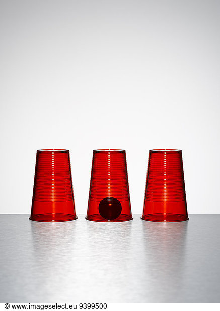 Ball under middle of three clear red cups