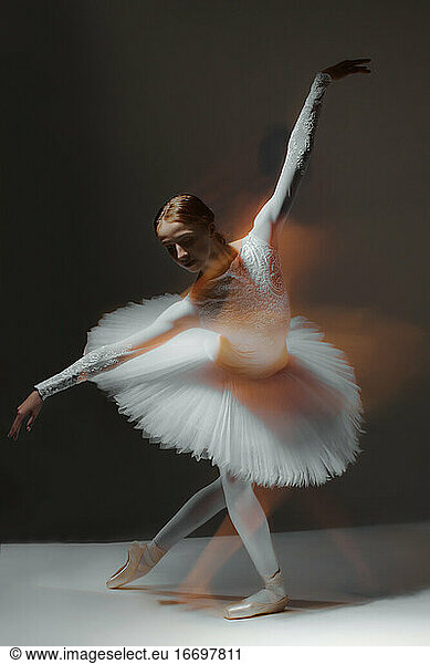 ballerina in white ballet dress dancing in dark class  motion blur